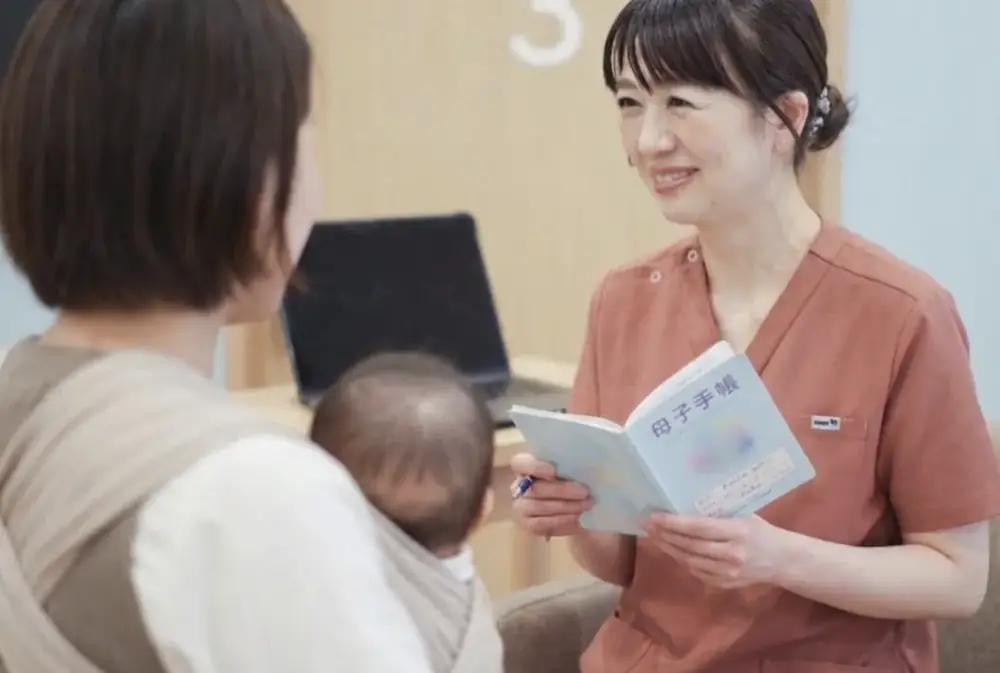 看護師が母子手帳を見ながら、保護者と赤ちゃんの成長について話す様子