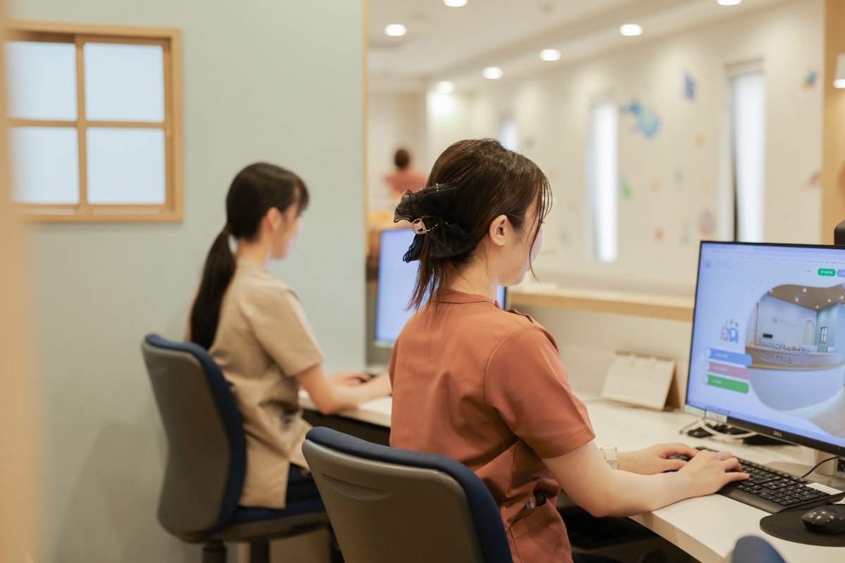 受付スタッフがパソコンで予約を確認する様子