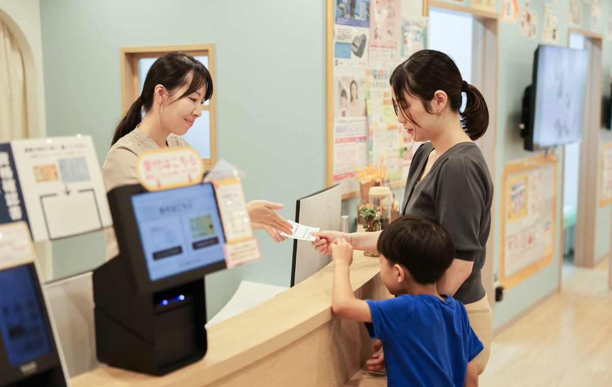 受付で保護者とお子さんにスタッフが対応している様子
