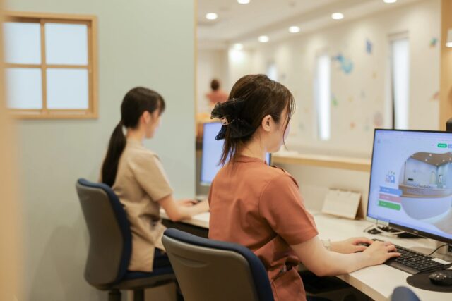 受付スタッフがパソコンで予約を確認する様子