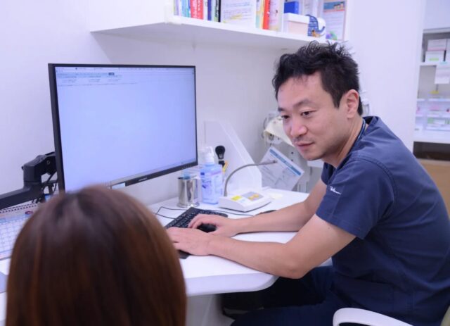 診察室で医師がパソコンを見ながら保護者と話す様子
