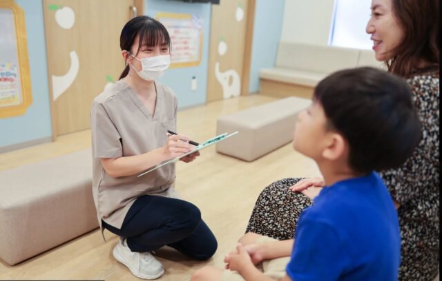 スタッフがしゃがんでお子さんと保護者に話を聞く様子